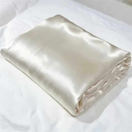 Ivory silk pillowcase folded on white bedding